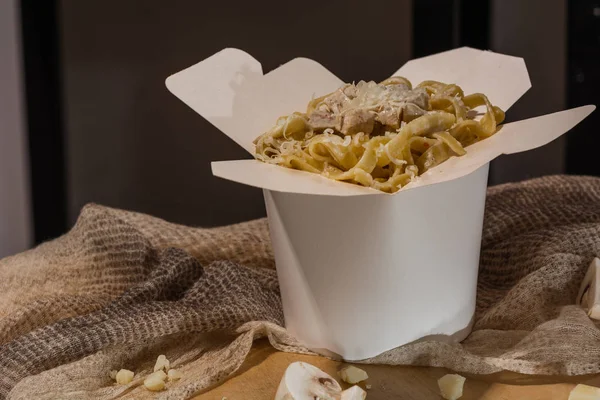 Homemade Pasta, Noodles, fettuccine Alfredo or Bolognese for take away in a white box on a wooden background close up shot. place for logo or copy paste text — Stock Photo, Image