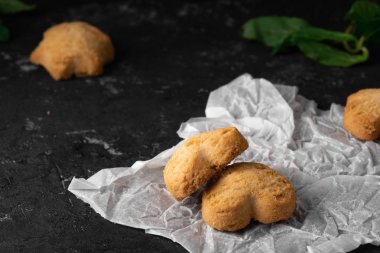 Beyaz destek kağıt ve koyu taş masa arka plan üzerinde Kahvaltı için zencefil ile ev yapımı coockies ile nane yaprağı ile Çay. Yakın çekim, makro