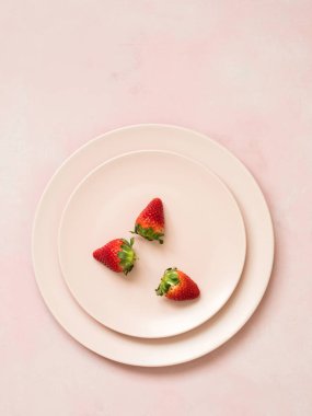 Çilek ile seramik plakalar üstten görünüm pembe pastel zemin üzerine