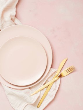 Pastel pembe bir arka plan üzerinde boş seramik tabak ve altın Çatal üstten görünüm