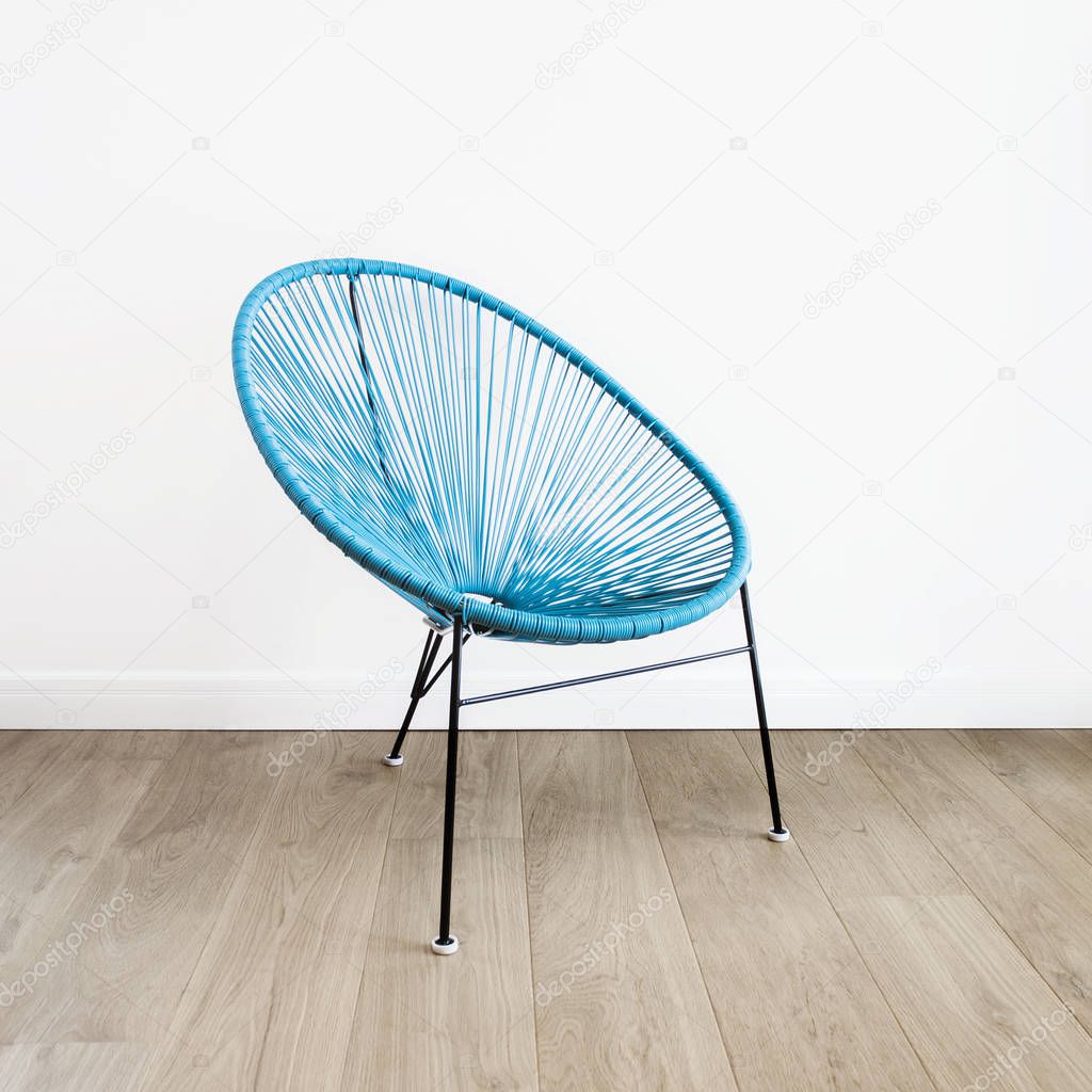 light blue acapulco chair on white wall background