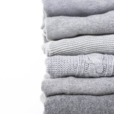 careful stack of grey woolen and cashmere sweaters on white background clipart