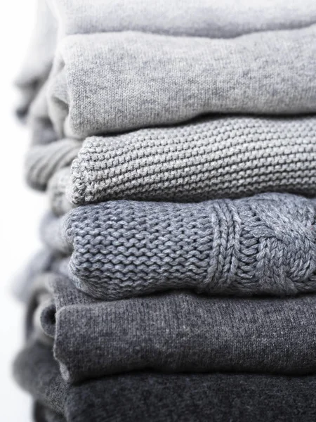 careful stack of grey woolen and cashmere sweaters on white background