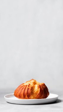 Muhallebi ile Fransız profiterol serpilir ve pudra şekeri gri arka plan üzerinde beyaz plaka üzerinde