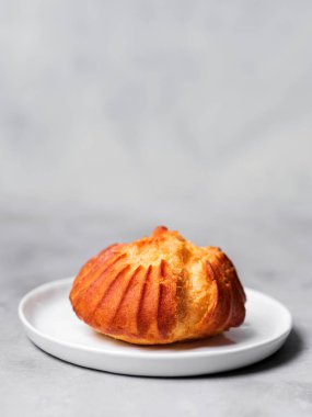 Muhallebi ile Fransız profiterol serpilir ve pudra şekeri gri arka plan üzerinde beyaz plaka üzerinde