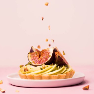pastel pembe üzerinde taze incir ile lezzetli tart düşen Antep fıstığı