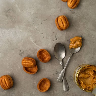 Vintage gümüş kaşıklarla karamelize süt ve gri beton zemin üzerine kahverengi kurabiye