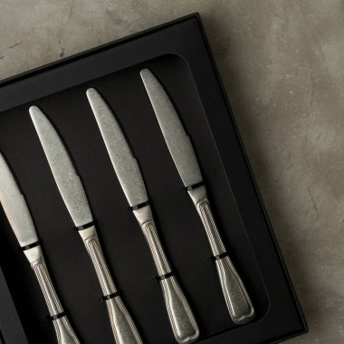 Gri beton zemin üzerine siyah kutu bıçaklar gümüş koleksiyonunun üstten görünüm