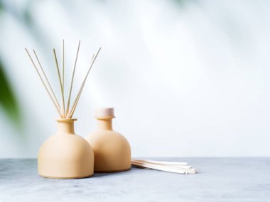 aroma reed fragrance diffusers with rattan sticks with palm leaf on light grey background clipart