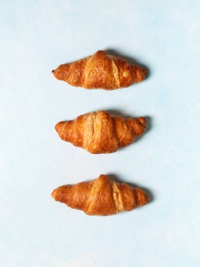 Pastel mavi zemin üzerine taze pişmiş kruvasanlar satırı 