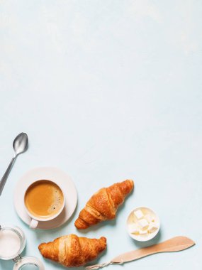 Fincan espresso kapsül, kruvasan ve pastel mavi zemin üzerine tereyağı ile 