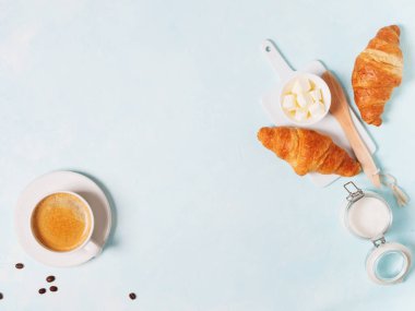 Fincan espresso kapsül, kruvasan, kahve çekirdekleri ve pastel mavi zemin üzerine tereyağı ile 