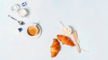 Kapsül, kruvasan ve tereyağı ile kahve espresso üstten görünüm pastel mavi zemin üzerine 