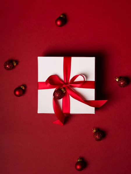 礼物白色盒子的顶部视图与红色丝带装饰与红色闪光球在红色背景 — 图库照片