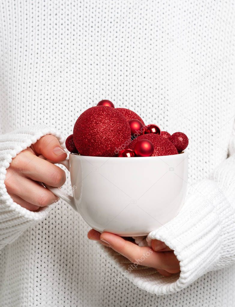 Woman holding white mug with red glitter christmas balls