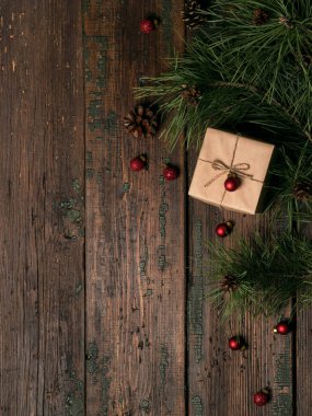 hediye kutusu dekore Kraft kağıt kırmızı glitter topları ile ve çam dalları üzerinde ahşap masa, koniler ile Noel ve Yılbaşı tatil kavramı 