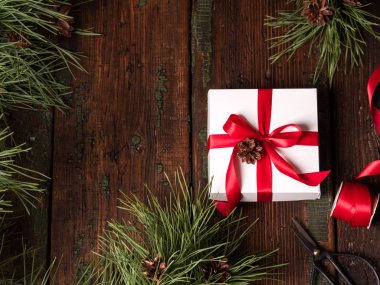 beyaz kutu kırmızı kurdele ile çam dalları ve koniler makas ve vintage ahşap arka plan, üstten görünüm kasette kaydırma ile dekore edilmiştir 