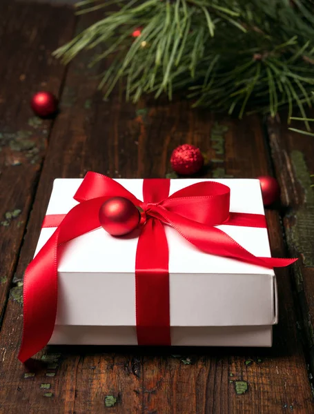 白色礼品盒装饰红色丝带和闪闪发光的球与松树分枝在黑暗的木背景 圣诞节概念 — 图库照片