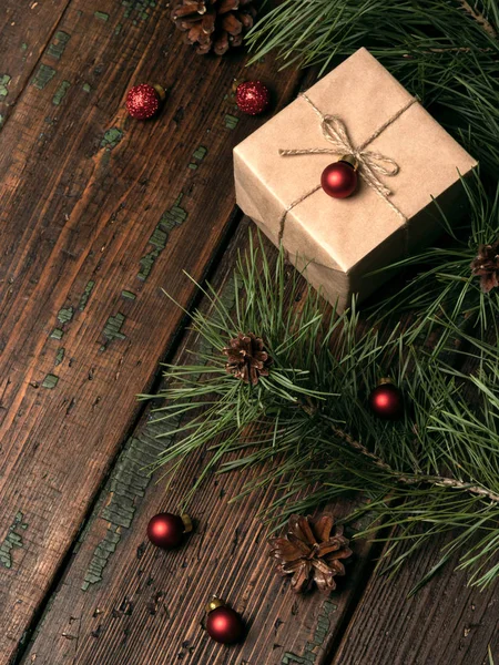 工艺纸礼品盒与圣诞节红色闪光小球和松树分枝与圆锥在木背景 — 图库照片