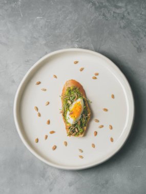 Tam tahıllı ekmek, yumurta ve ayçiçeği tohumu ve seramik beyaz gri beton arka plan, üstten görünüm, diyet gıda kavramı, üzerinde gluten-Alerjik tabakta serpilir siyah tuz taze mini otlar ile avokado kaplama   