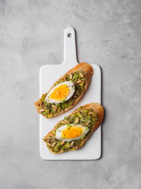 Tam tahıllı yumurta ile kaplama avokado ve ayçiçeği tohumu ve glutensiz gri beton arka plan, üstten görünüm, diyet gıda kavramı, üzerinde seramik beyaz tahta üzerinde hizmet serpilir siyah tuz taze mini otlar kızartır 
