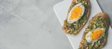Tam tahıllı yumurta ile kaplama avokado ve ayçiçeği tohumu glutensiz gri beton arka plan, üstten görünüm, diyet gıda kavramı, üzerinde seramik beyaz tahta üzerinde hizmet ile taze mini otlar kızartır 