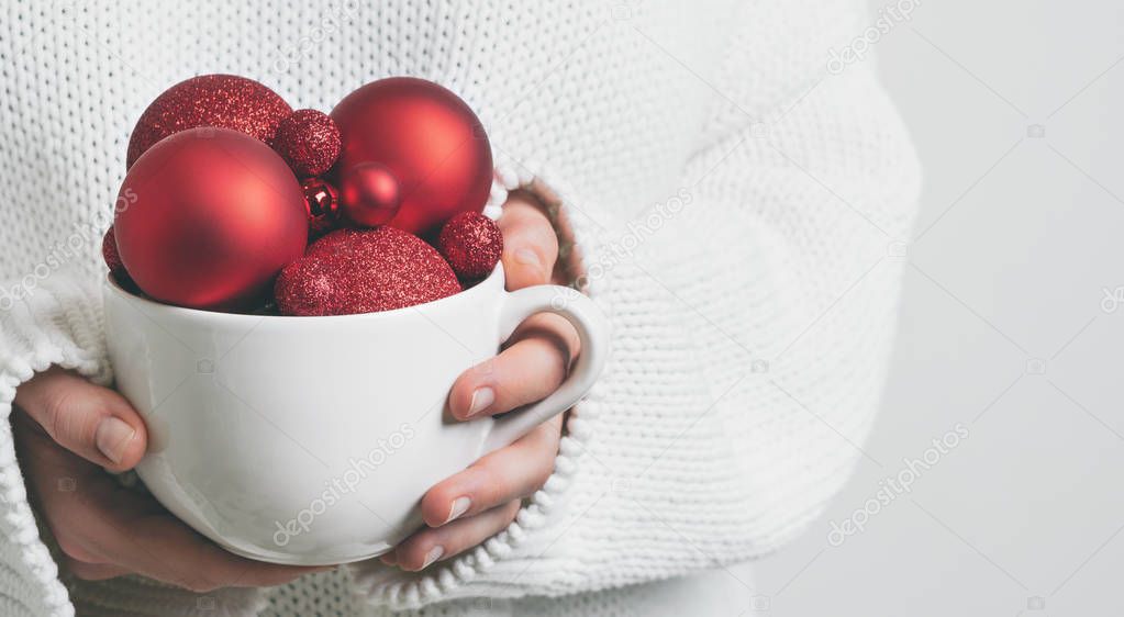 Woman in warm white sweater holding mug in hands with Christmas balls, Concept for New year mock-up 