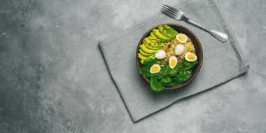 Ahşap kase üzerinde gri keten havlu üstten görünüm salatası bulgur, ıspanak, avokado ve Bıldırcın yumurta