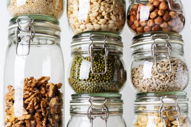 Görünümü Kapat cam kavanozlar ile kaşu, fındık, ceviz, fıstık, mung fasulye, quinoa, ışık arka plan ayçiçeği tohumu
