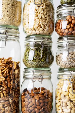 Görünümü Kapat cam kavanozlar ile kaşu, fındık, ceviz, fıstık, mung fasulye, quinoa, ışık arka plan ayçiçeği tohumu