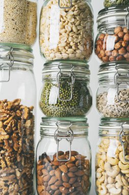 Görünümü Kapat cam kavanozlar ile kaşu, fındık, ceviz, fıstık, mung fasulye, quinoa, ışık arka plan ayçiçeği tohumu