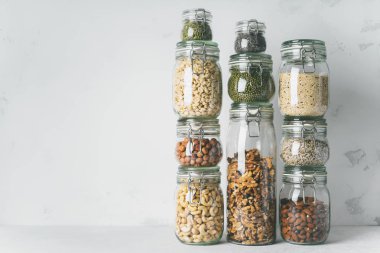 Kuleleri cam kavanoz badem, kaju fıstığı, fıstık, fındık, ceviz ve Chia tohum, mung fasulye, ışık arka plan üzerinde quinoa, Ayçiçeği tohumları