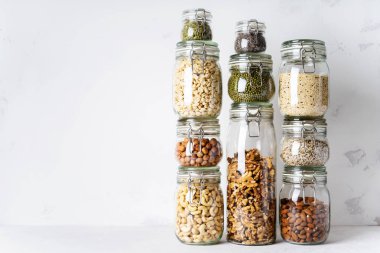 Kuleleri cam kavanoz badem, kaju fıstığı, fıstık, fındık, ceviz ve Chia tohum, mung fasulye, ışık arka plan üzerinde quinoa, Ayçiçeği tohumları