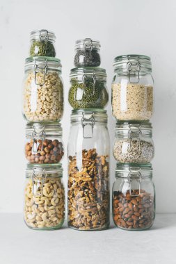 Kuleleri cam kavanoz badem, kaju fıstığı, fıstık, fındık, ceviz ve Chia tohum, mung fasulye, ışık arka plan üzerinde quinoa, Ayçiçeği tohumları