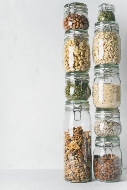 Kuleleri cam kavanoz badem, kaju fıstığı, fıstık, fındık, ceviz ve Chia tohum, mung fasulye, ışık arka plan üzerinde quinoa, Ayçiçeği tohumları