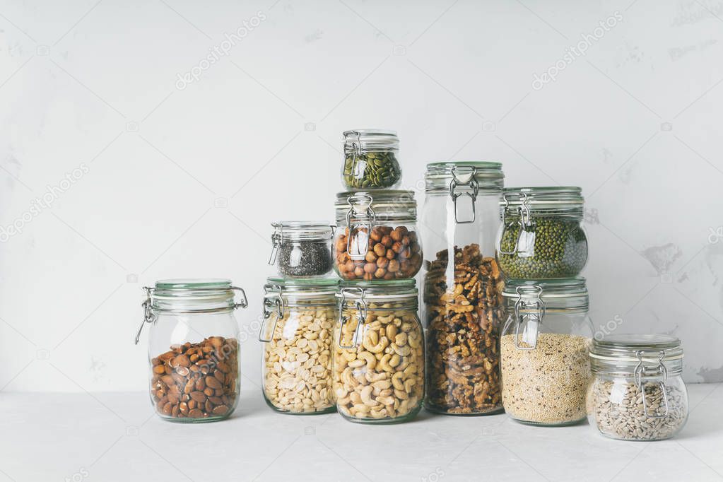 Collection of glass jars with almonds, cashews, peanuts, hazelnuts, walnuts and Chia seeds, mung beans, quinoa, sunflower seeds
