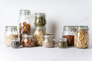 Cam kavanozlar badem, kaju fıstığı, fıstık, fındık, ceviz ve Chia Tohumu, mung fasulye, quinoa, ışık arka plan ayçiçeği tohumu ile