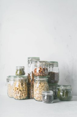 Cam kavanozlar badem, kaju fıstığı, fıstık, fındık, ceviz ve Chia Tohumu, mung fasulye, quinoa, ışık arka plan ayçiçeği tohumu ile