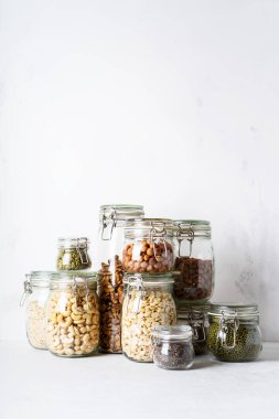 Cam kavanozlar badem, kaju fıstığı, fıstık, fındık, ceviz ve Chia Tohumu, mung fasulye, quinoa, ışık arka plan ayçiçeği tohumu ile