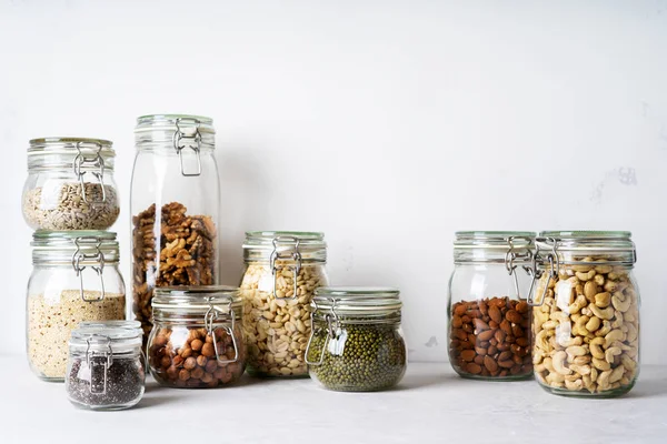 Cam kavanozlar badem, kaju fıstığı, fıstık, fındık, ceviz ve Chia Tohumu, mung fasulye, quinoa, ışık arka plan ayçiçeği tohumu ile