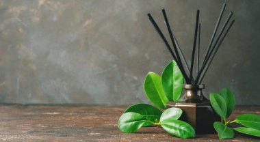 Aroma reed difüzör şişe rattan sopa ve yeşil koyu kahverengi zemin üzerinde bırakır