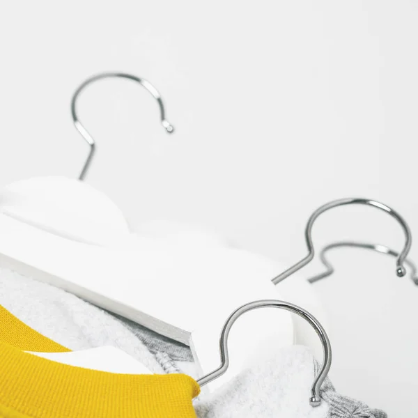 Pile of stylish clothes in pastel colors on white hangers over white background