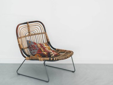 Üzerinde renkli mozaik halk yastık geometrik süsleme ile metal ayaklı modern rattan koltuk