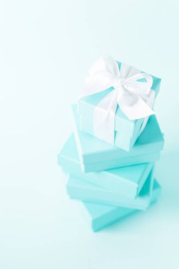 Tiffany mavi renk pastel arka plan üzerinde beyaz ipek kurdele ile mavi kutu yığını bağlı