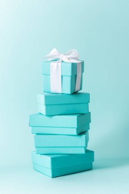 Tiffany mavi renk pastel arka plan üzerinde beyaz ipek kurdele ile mavi kutu yığını bağlı
