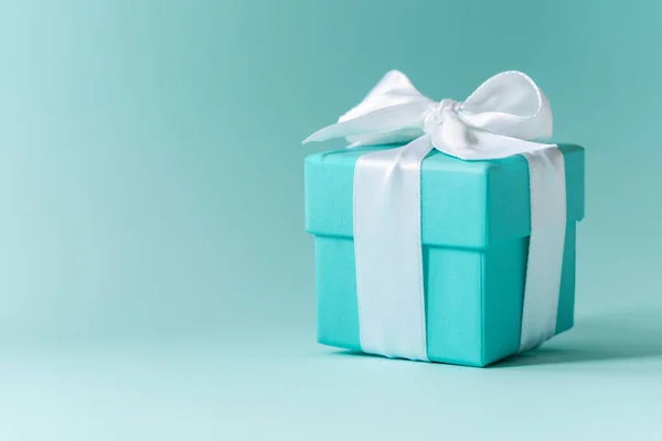 Tiffany mavi renk kutusunu pastel arka plan üzerinde beyaz ipek kurdele ile bağlı 