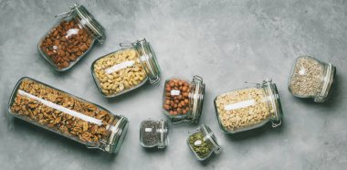 Collection of almonds, cashews, peanuts, hazelnuts, walnuts and Chia seeds, sunflower and pumpkin seeds in glass jars on concrete background clipart