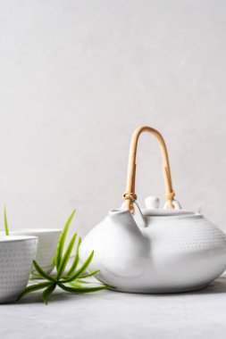 Yeşil çay, bardak ve çaydanlık bambu ile ayarla Asya gri arka plan üzerinde bırakır 