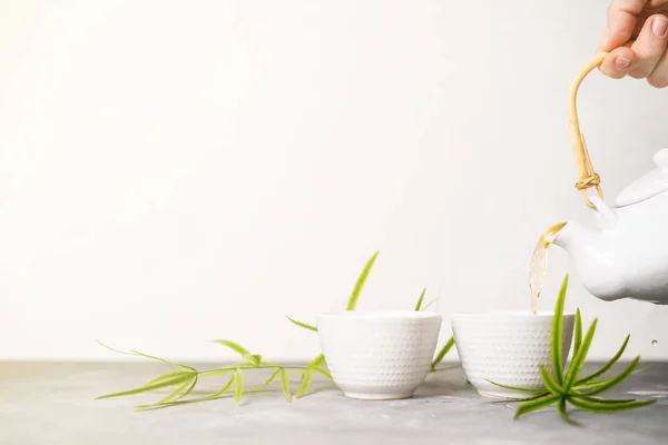 女性手将绿茶从茶壶倒进杯中 背景为白色背景 并有复制空间 亚洲茶具 — 图库照片