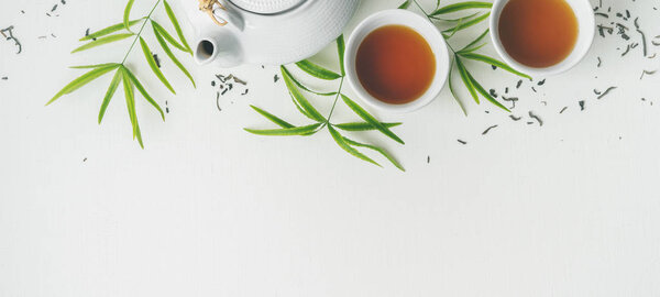 Asian set with green tea, cups and teapot on white background with green leaves 
